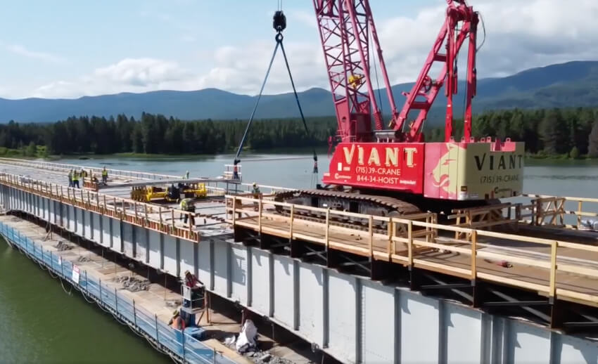 bridge build over the lake with Viant red crane and workers installing the bridge
